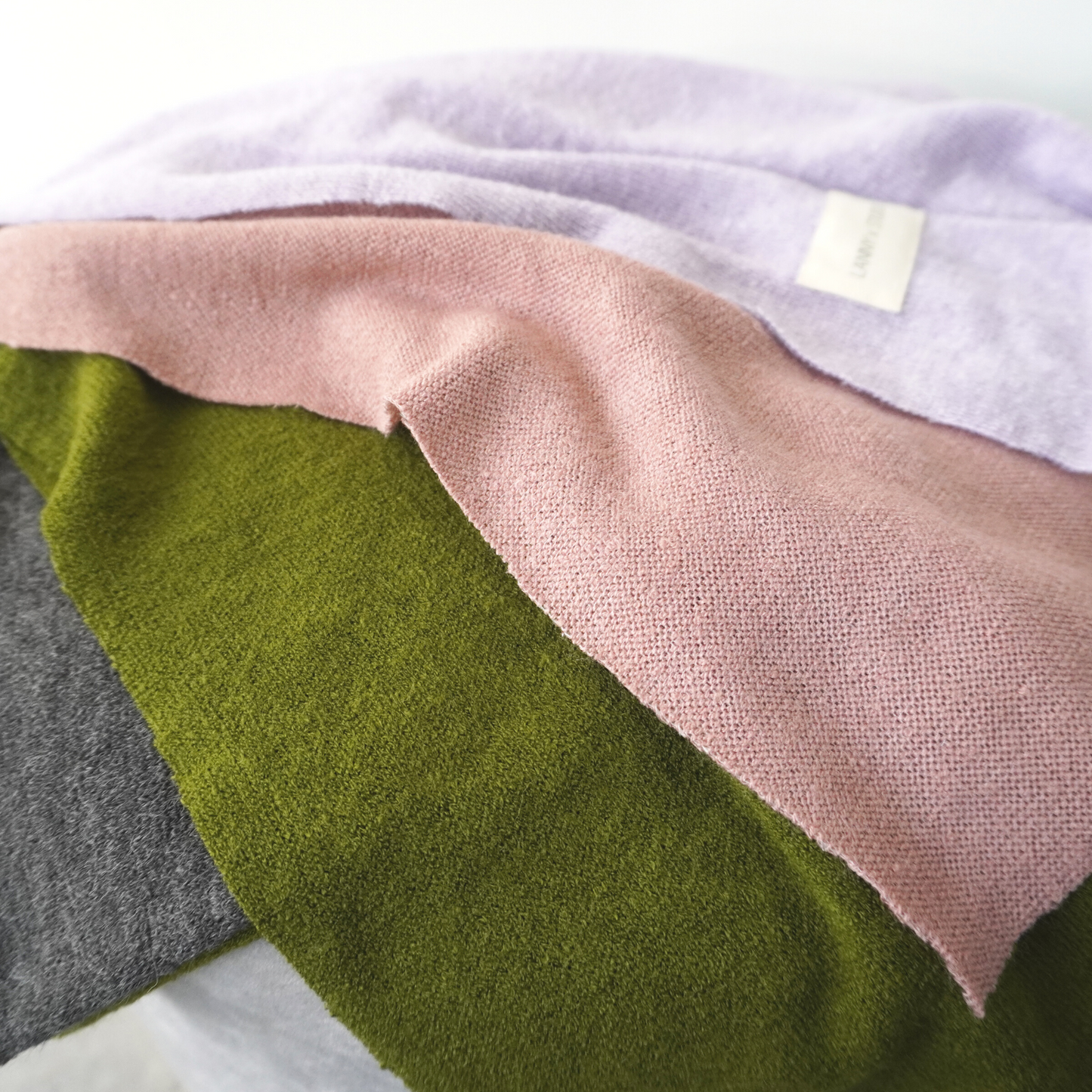 Pink, Green, Lilac and charcoal panelled throw in knit fabric. Folded close up view.