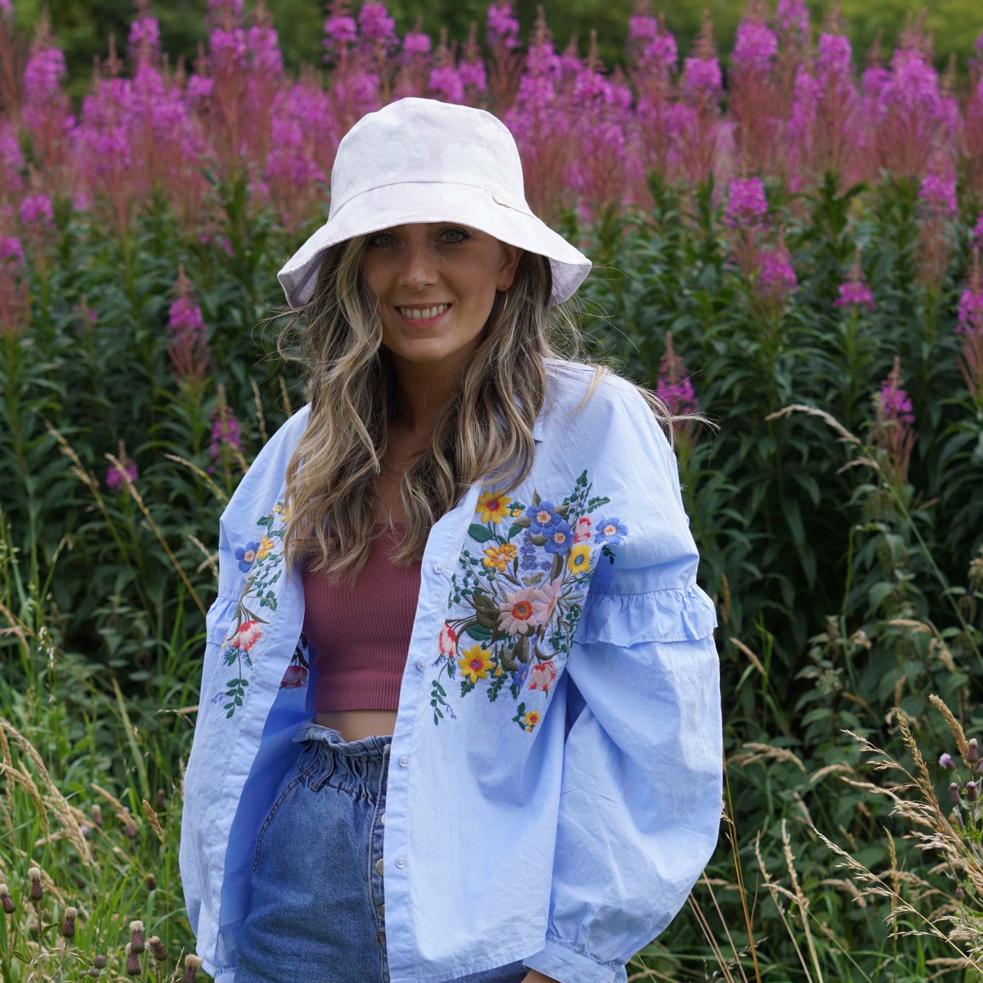 Lilac and White Floral Bucket Hat, photographed on a women smiling with a floral background. 