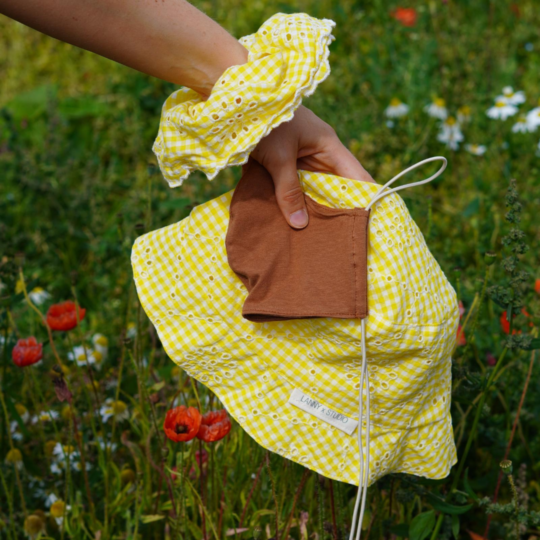 Yellow and white gingham and broiderie anglaise extra large scrunchie with scalloped edge, shown with matching bucket hat and caramel jersey face mask. 