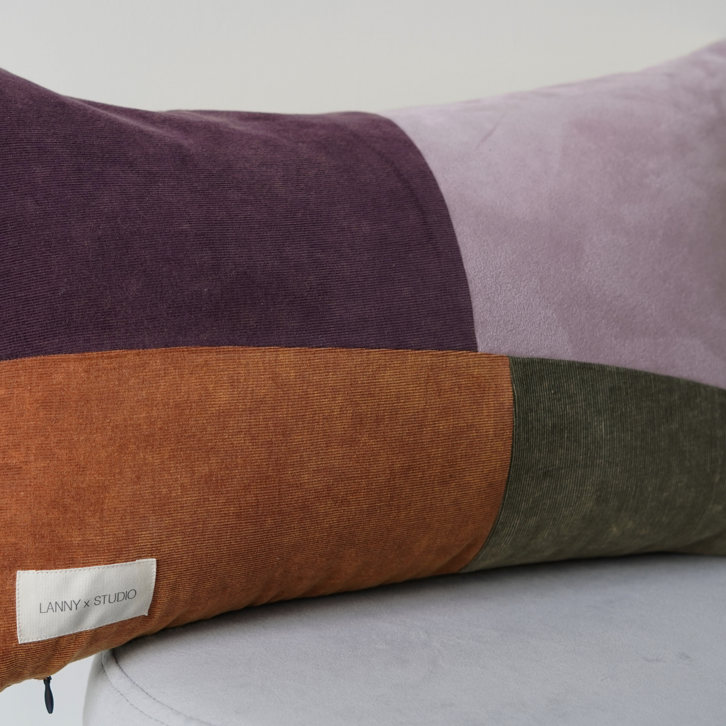 Orange, Purple, Green and Lilac panelled rentable cushion with branded LannyxStudio label. Close up view.