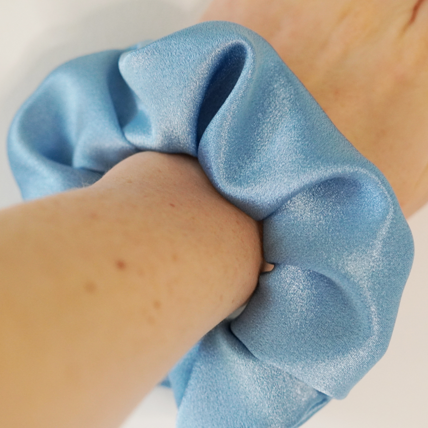 Blue satin scrunchie on wrist