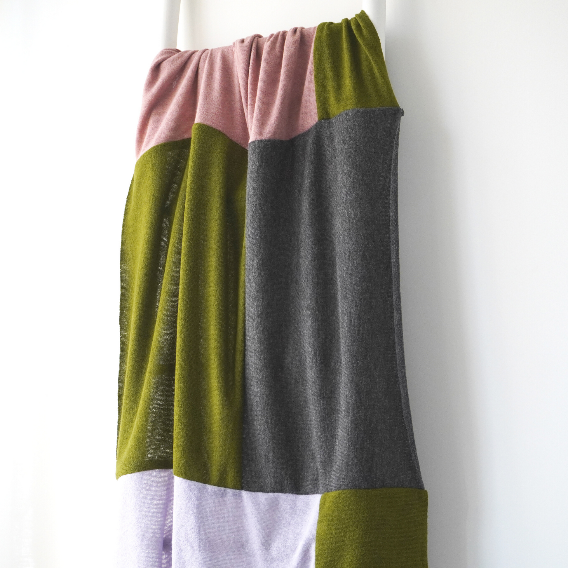 Pink, Green, Lilac and charcoal colour block throw in knit fabric. Close up view 