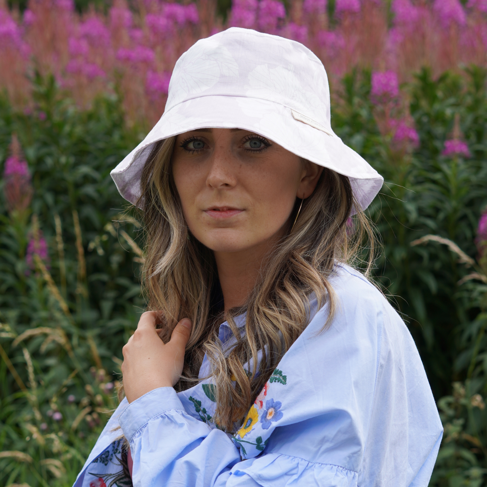 Lilac and White Floral Bucket Hat, photographed on a women directly facing the camera.   