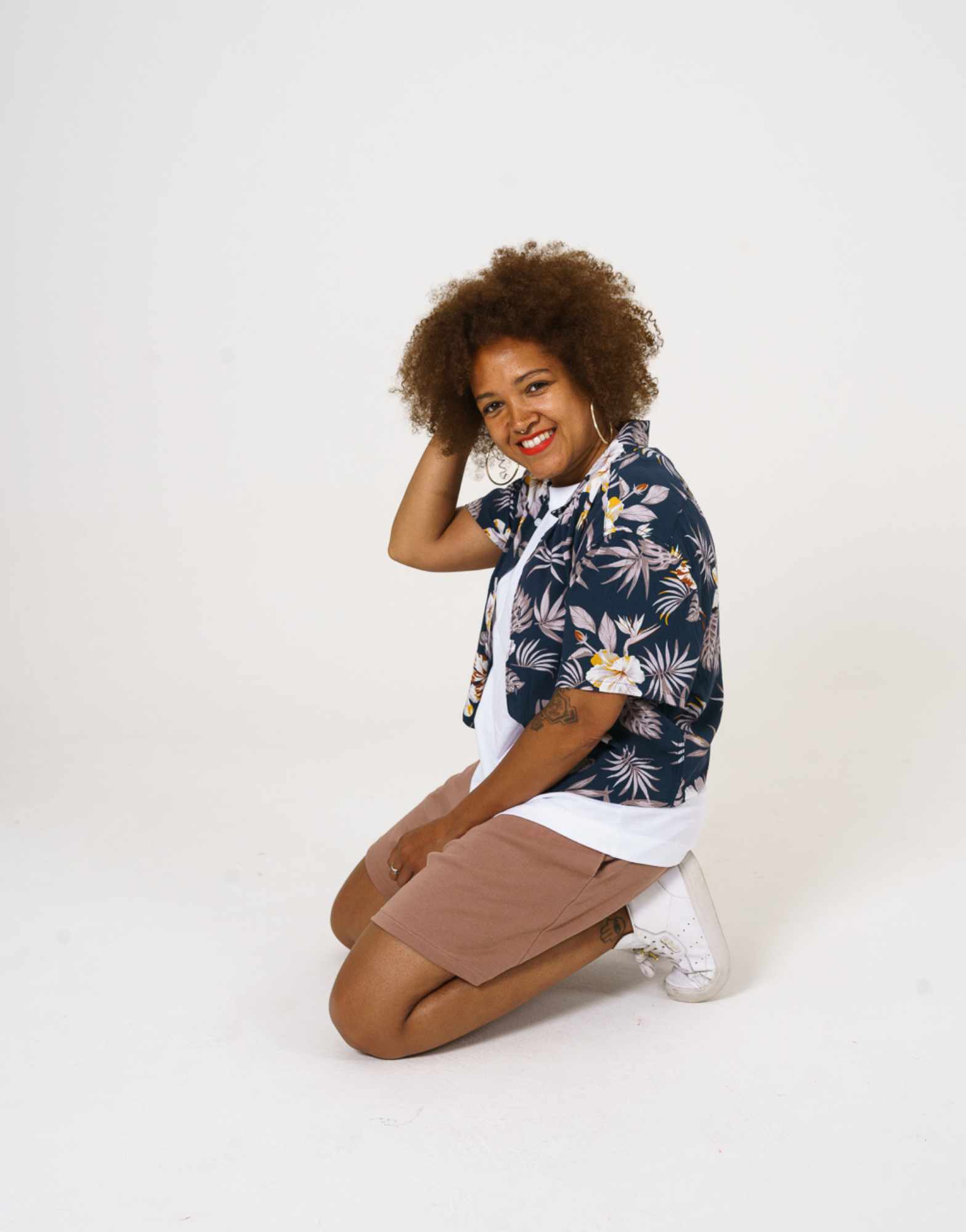 Upcycled womens Navy Floral Viscose Shirt with cropped hem, styled over a white t-shirt and paired with our cinnamon jersey shorts and shown with model kneeling down.  