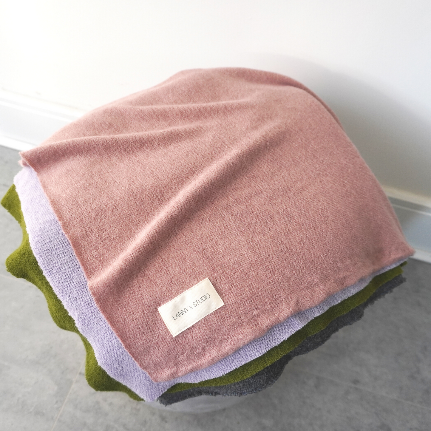 Pink, Green, Lilac and charcoal colour block throw in knit fabric with LannyxStudio Branded label. View from top folded. 