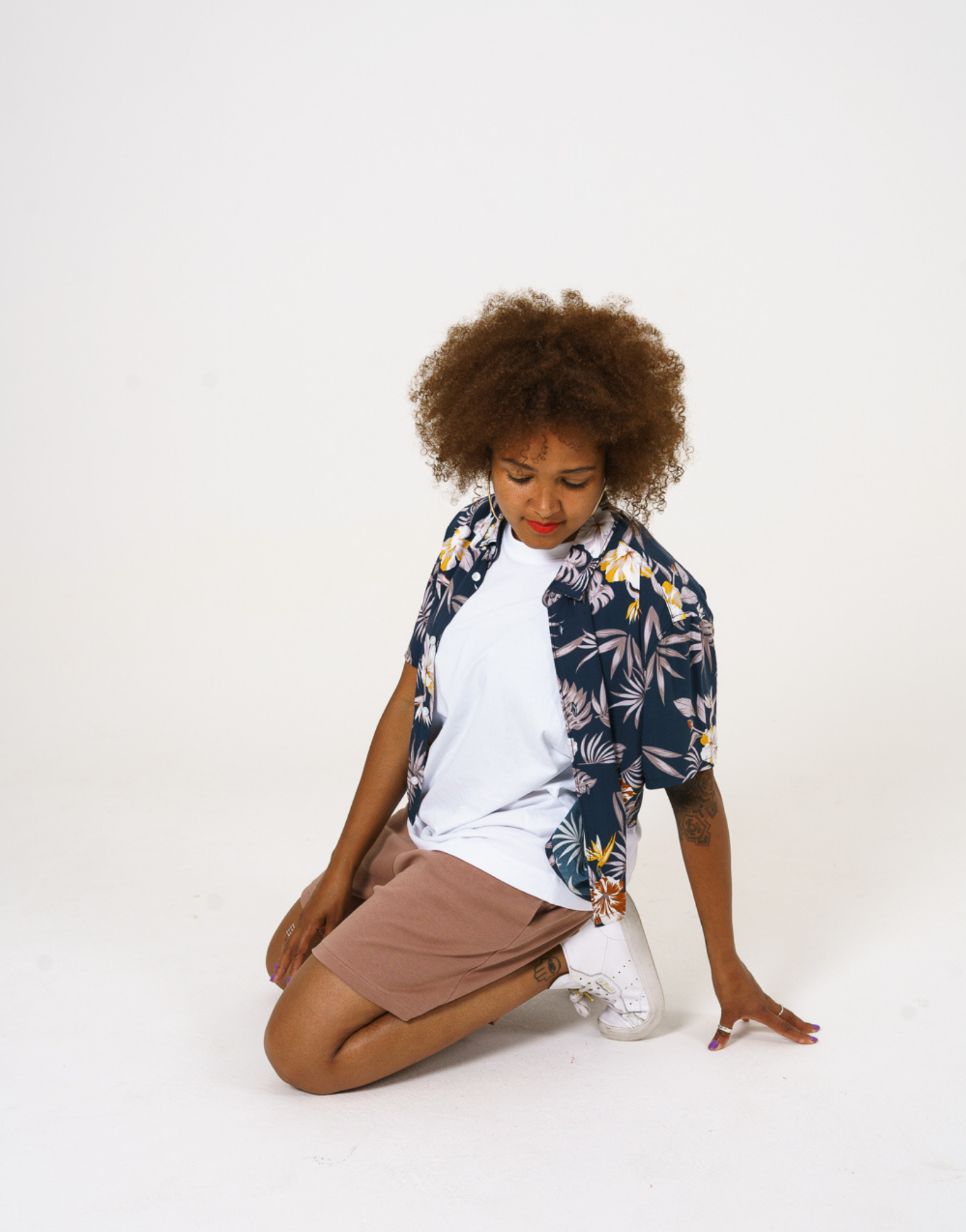 Upcycled womens Navy Floral Viscose Shirt with cropped hem, styled over a white t-shirt and paired with our cinnamon jersey shorts, shown on model kneeling down. 