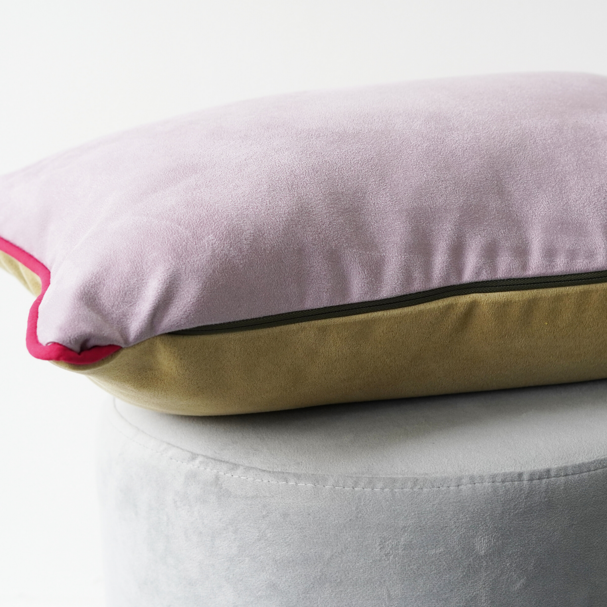 Yellow and lilac suede look rectangle cushion with contrast fuchsia piping and khaki zip. Close up view of cushion laying flat to show features.