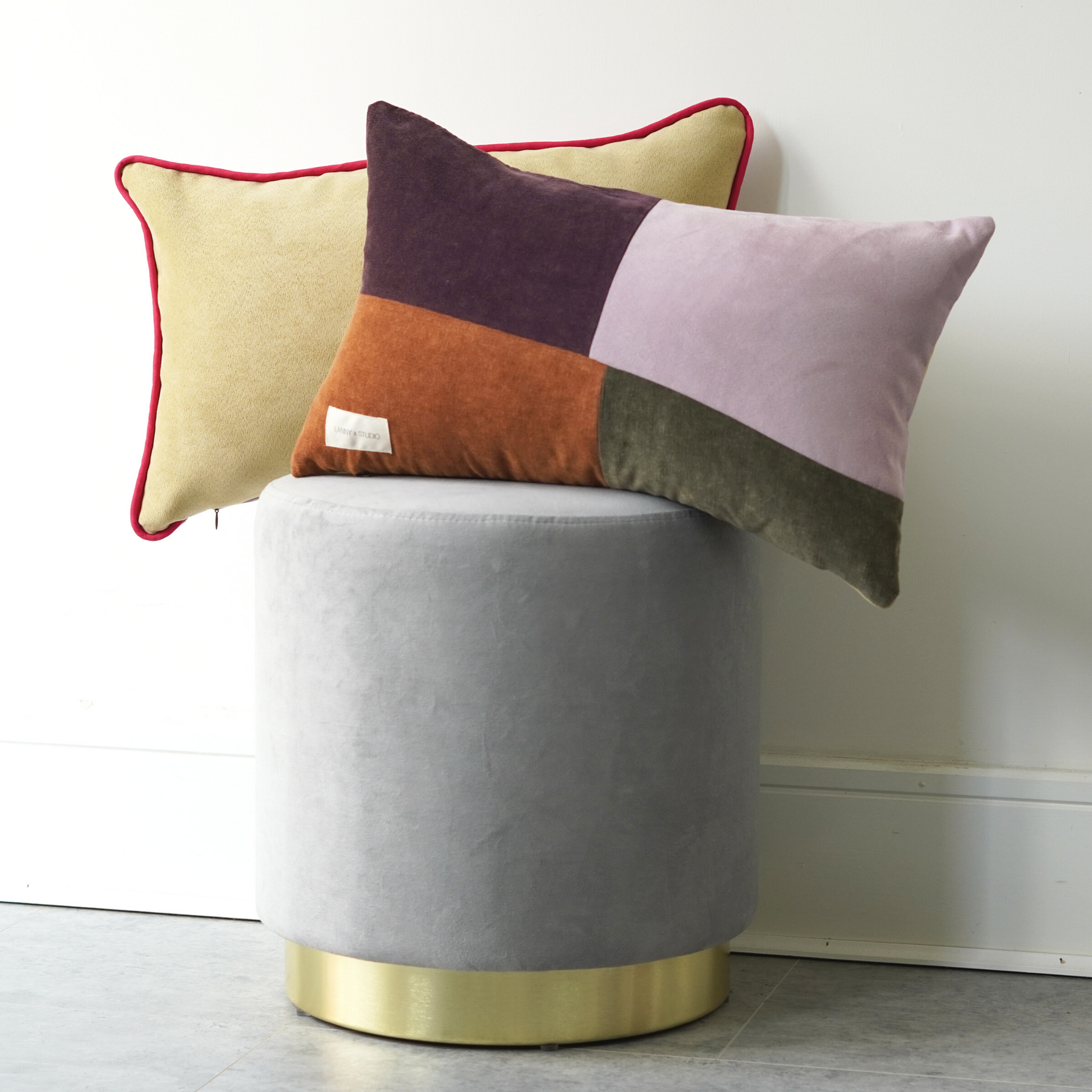 Orange, Purple, Green and Lilac panelled rentable cushion with branded LannyxStudio label partnered with the yellow suede look rectangle cushion with contrast Fuchsia piping. 
