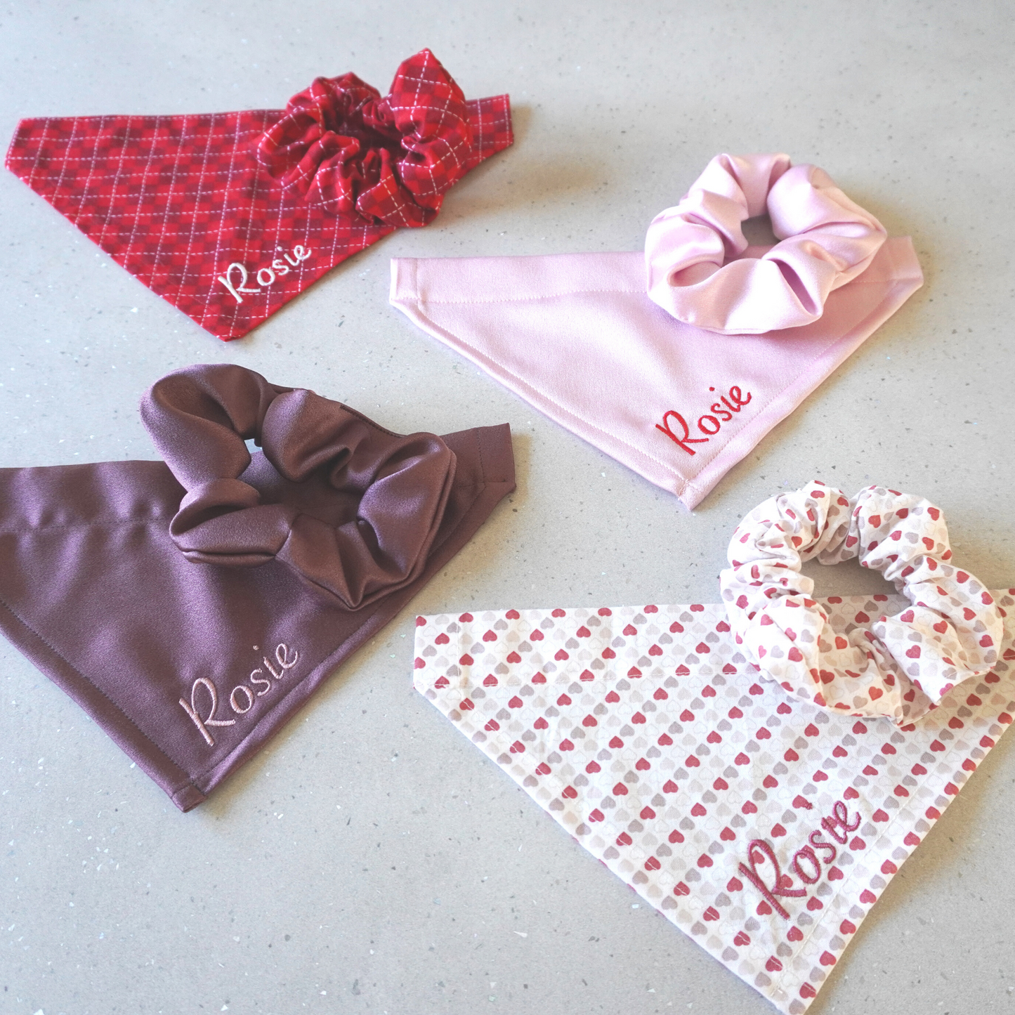 Image showing our female pet bandana collection, all available with matching scrunchie. Red check, pink heart print, purple and pink satin. 